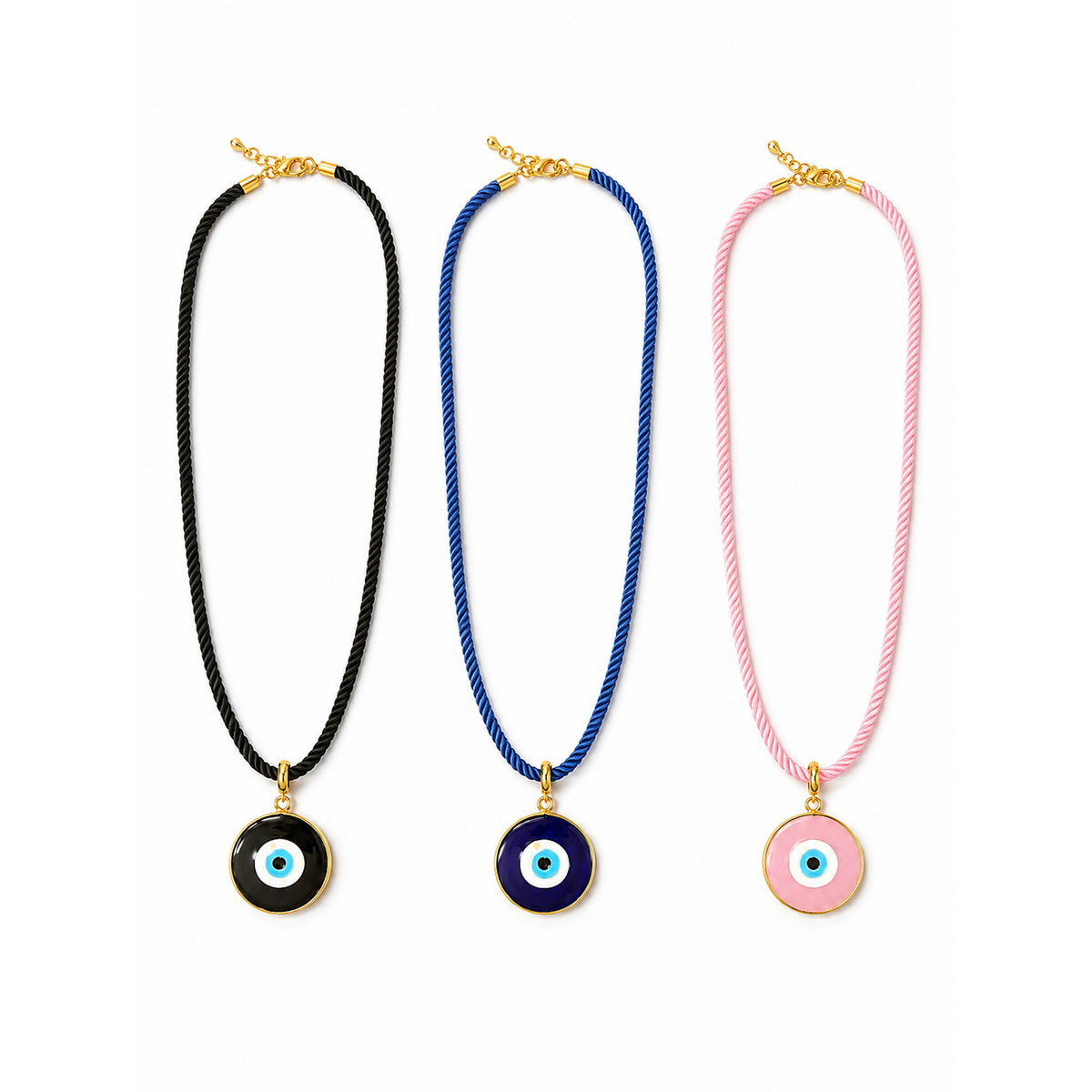 Three evil eye cord necklaces with gold-tone pendants are displayed side-by-side on a white background. The necklaces feature black, blue, and pink cords, each with a circular evil eye pendant in a different color: black, dark blue, and pink, respectively.
